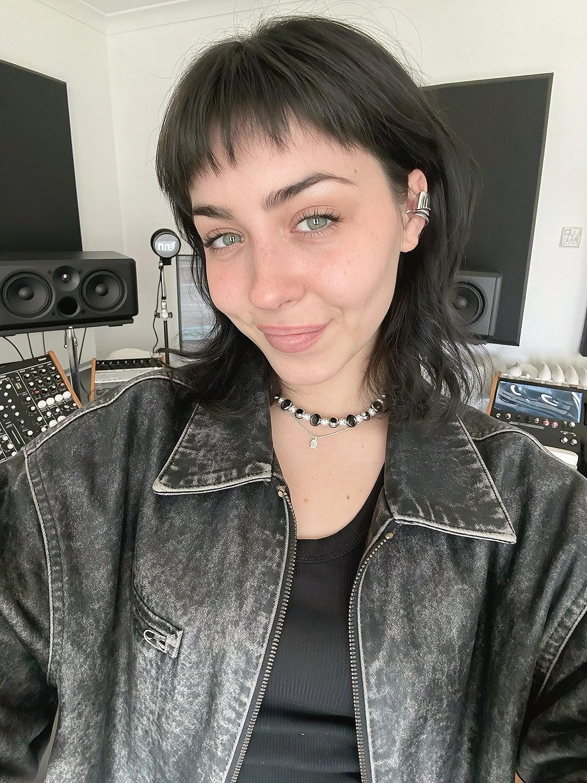 Close shoulder-up candid portrait of a fictional alt-pop / electronic singer in her own music recording studio