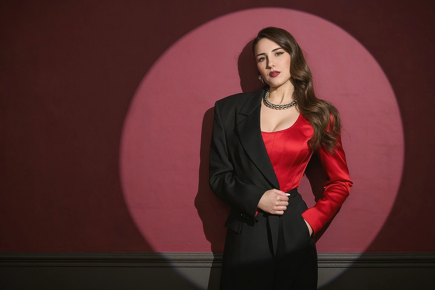 High-fashion editorial album portrait of a fictional adult pop star in ruby satin and sculptural black tailoring, with dramatic studio lighting
