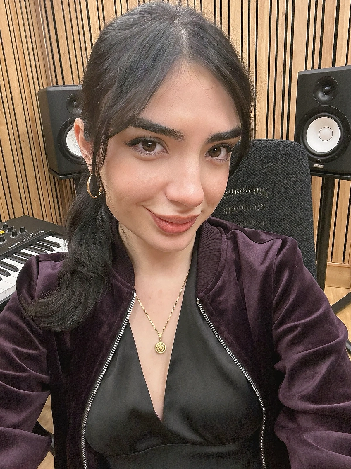 Close shoulder-up candid portrait of a fictional young adult r&b / alt-soul artist smiling naturally in their own music recording studio