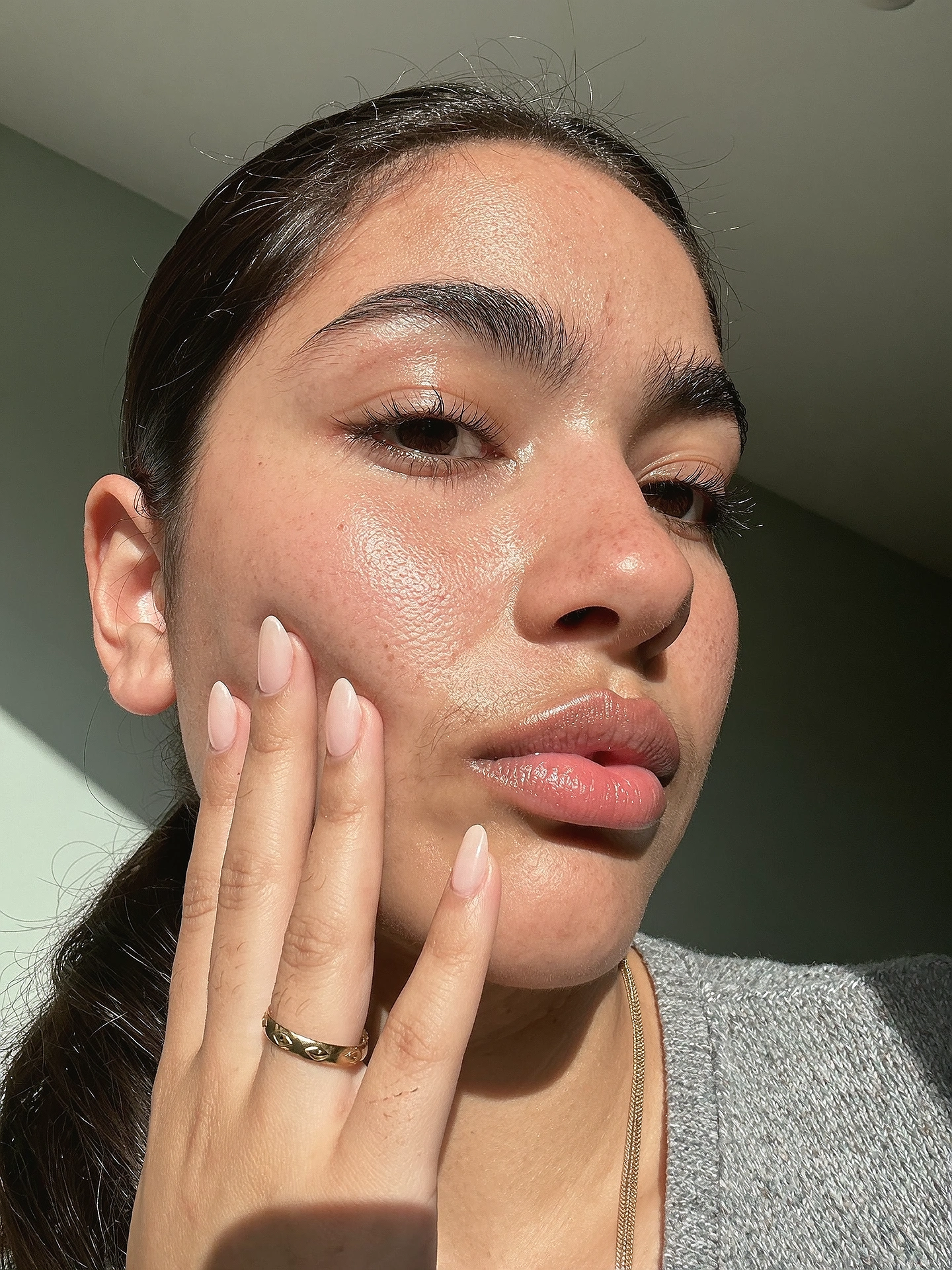 Sunlit close-up with a hand against the cheek and visible natural skin texture